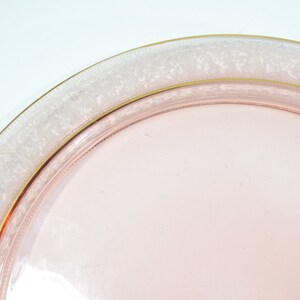 Puede incluir: Un plato de servir de vidrio rosa con un borde blanco y dorado. El plato tiene un delicado patr&oacute;n floral alrededor del borde.