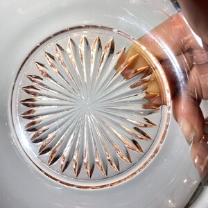 Pode incluir: Uma tigela de vidro transparente com uma borda rosa e um padr&atilde;o de estrela no fundo.