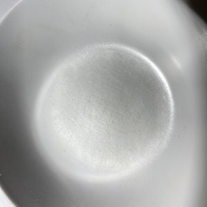 May include: A white ceramic bowl with a smooth, slightly textured surface. The bowl has a circular shape and a slight lip around the edge.