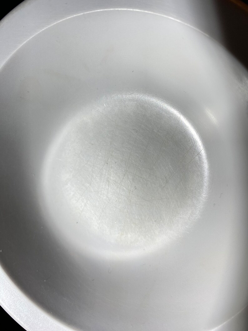 May include: A white ceramic bowl with a smooth, slightly textured surface. The bowl has a circular shape and a slight lip around the edge.