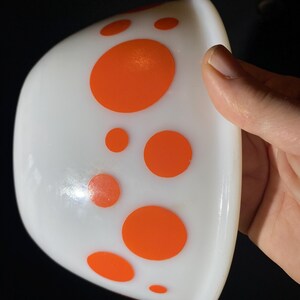 May include: White ceramic bowl with a band of orange polka dots around the rim.