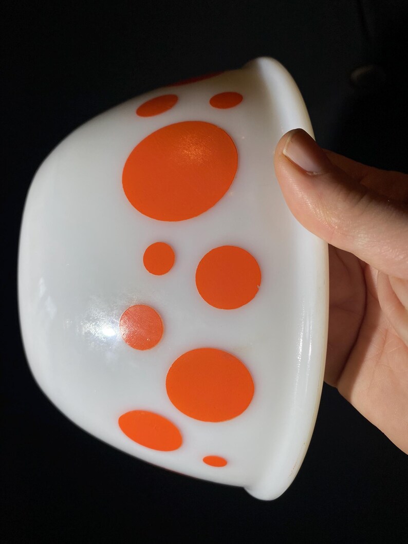 May include: White ceramic bowl with a band of orange polka dots around the rim.