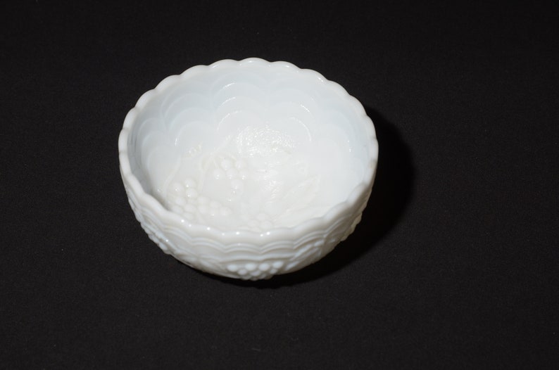 K&ouml;nnte beinhalten: Eine wei&szlig;e Schale mit gewelltem Rand und einem Traubenmuster. Die Schale besteht aus undurchsichtigem Glas und hat eine strukturierte Oberfl&auml;che. Die Schale ist wahrscheinlich Vintage und eignet sich zum Servieren kleiner Portionen.