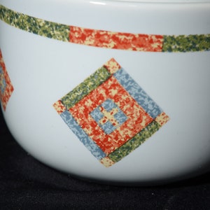 Puede incluir: Taz&oacute;n de cer&aacute;mica blanco con un patr&oacute;n geom&eacute;trico verde, rojo y azul. El patr&oacute;n es una serie de cuadrados dentro de cuadrados.