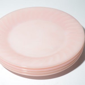 Pode incluir: Uma pilha de três pratos de sobremesa de vidro rosa com um design de redemoinho.