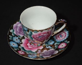 Juego de taza y platillo vintage con rosas grandes en tonos rosa, violeta y azul sobre fondo dorado. Ribete dorado. Hecho en China.