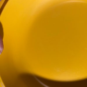 May include: A yellow plastic bowl with a smooth surface. The bowl is empty and appears to be new.