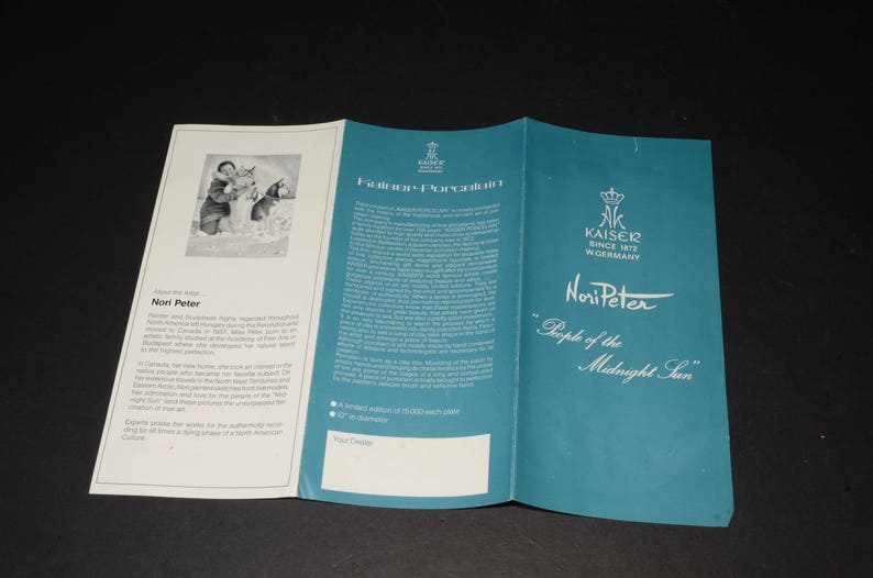 May include: A tri-fold brochure for Kaiser Porcelain, featuring artist Nori Peter. The teal cover displays the text "Nori Peter" and "People of the Midnight Sun". The brochure has white interior pages with text and an illustration.