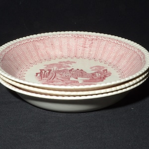May include: Three white ceramic bowls with a pink floral pattern and a scalloped edge. The bowls are stacked on top of each other.