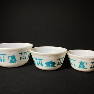 May include: Set of three white mixing bowls with a teal blue kitchen design. The bowls are nested together, with the largest bowl in the front and the smallest bowl in the back.
