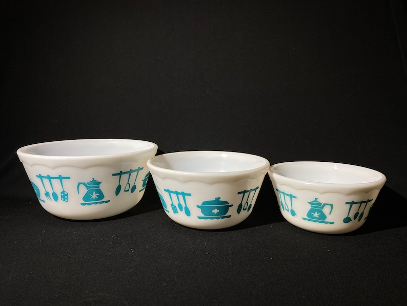 May include: Set of three white mixing bowls with a teal blue kitchen design. The bowls are nested together, with the largest bowl in the front and the smallest bowl in the back.