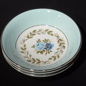 May include: Three blue and white ceramic bowls with a floral design. The bowls have a light blue rim and a gold trim.