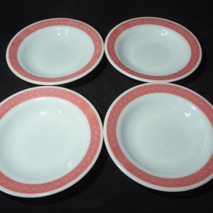 Può includere: Quattro ciotole in ceramica bianca con un motivo floreale rosa attorno al bordo. Le ciotole sono tutte vuote e sono disposte a forma di quadrato.