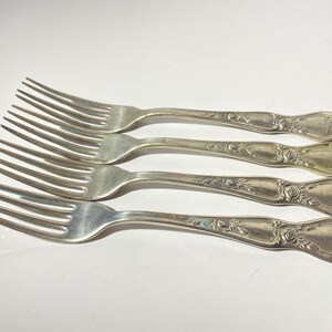 Pode incluir: Conjunto de quatro garfos de prata com desenhos de rosas ornamentados nas alças.