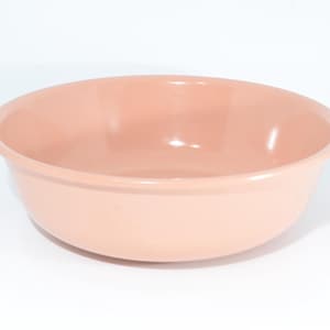 Puede incluir: Un cuenco rosa claro con forma redondeada. El cuenco tiene un acabado liso y brillante y un borde ancho. El cuenco está vacío y descansa sobre una superficie blanca. Ideal para la cocina.