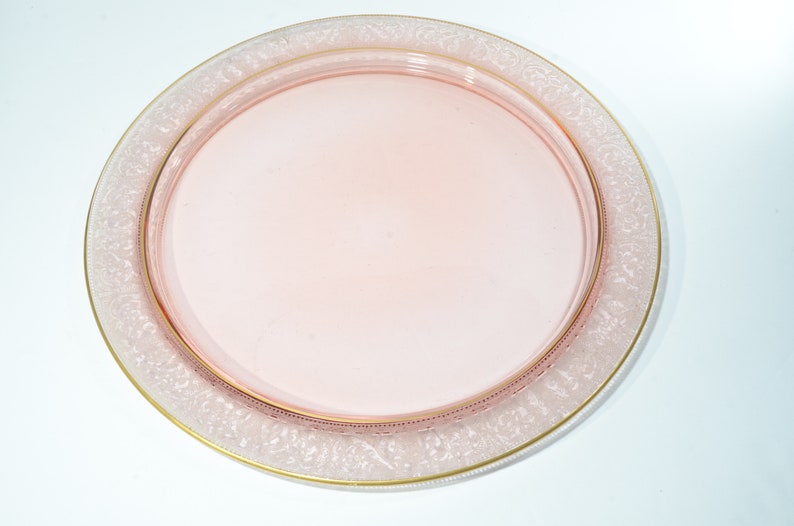 Puede incluir: Una bandeja de servir de vidrio rosa con un borde dorado y un delicado dise&ntilde;o grabado alrededor del borde.