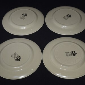 May include: Four cream-colored ceramic dinner plates with a black "Killa Craft" logo on the bottom.
