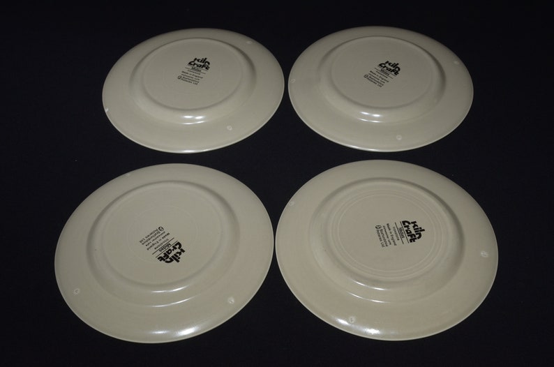 May include: Four cream-colored ceramic dinner plates with a black "Killa Craft" logo on the bottom.