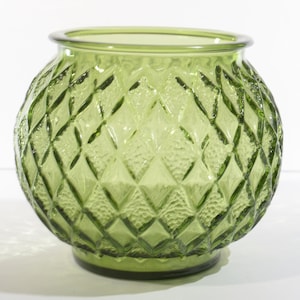 May include: A green glass vase with a diamond pattern. The vase is round and has a wide mouth.