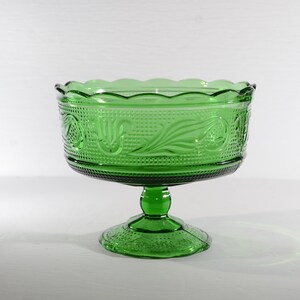 May include: A green glass pedestal bowl with a scalloped rim and an embossed floral design.
