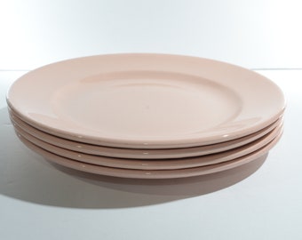 Puede incluir: Un juego de cuatro platos de cena de cerámica de color rosa pálido.