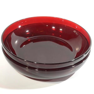 May include: A stack of three ruby red glass bowls. The bowls have a smooth, glossy finish and a slightly curved shape. The rims are a brighter shade of red than the interior. The bowls are nested together, showcasing their depth and design.