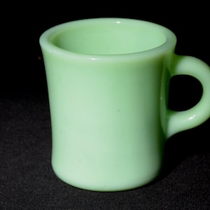 Peut inclure: Une tasse en céramique vert clair avec une anse arrondie. La tasse est faite d'un matériau lisse et opaque.