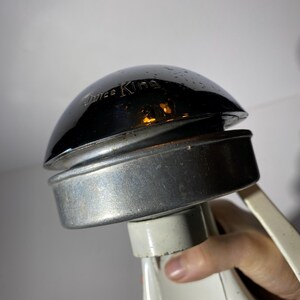 May include: Close-up of a vintage Juice King juicer with a chrome top and a white base. The juicer has a lever on the side.