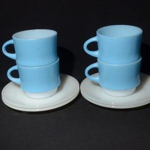 Może przedstawiać: Dwa zestawy ułożonych na sobie niebieskich i białych ceramicznych filiżanek do kawy z pasującymi białymi spodkami.