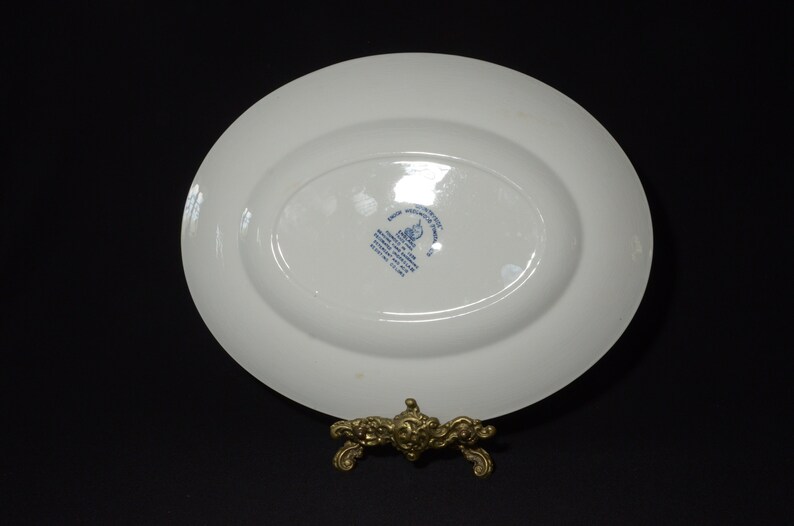 Op de afbeelding: Witte ovale serveerschaal met een blauw-wit logo aan de onderkant. Het logo bevat de tekst "Made in England" en "Royal Doulton".