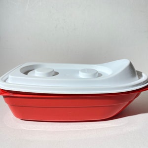 May include: A red plastic container with a white lid. The lid has two small white knobs on top.
