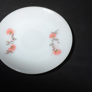 May include: A white ceramic bowl with a floral design. The bowl has a simple, elegant design with pink flowers and green leaves.