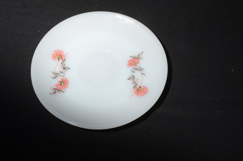 May include: A white ceramic bowl with a floral design. The bowl has a simple, elegant design with pink flowers and green leaves.