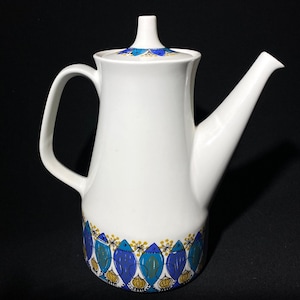 May include: White ceramic coffee pot with a blue and gold floral design. The pot has a rounded body and a spout on the side.
