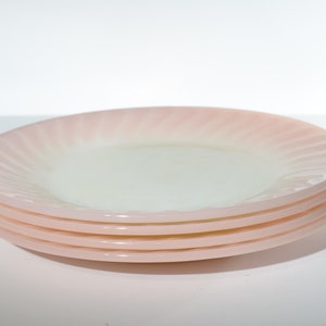 May include: A stack of four pink and white swirl patterned glass dinner plates.