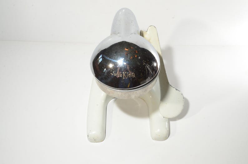 May include: White ceramic citrus juicer with a chrome top. The top has the words "Juice King" embossed on it.