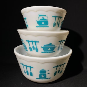 May include: Three white mixing bowls with a blue and white kitchen utensil design. The bowls are stacked on top of each other.
