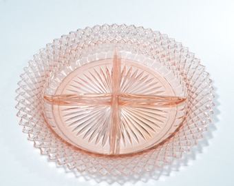 May include: A pink glass divided serving dish with a diamond pattern around the edge and a sunburst pattern in the center.