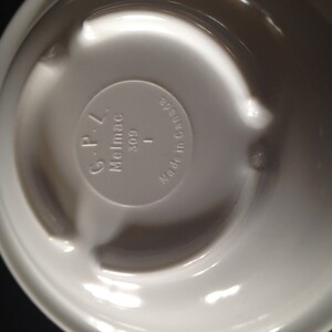 May include: White ceramic bowl with a raised rim and a circular design on the bottom. The bottom of the bowl has the text "Melmac G-P-L 309 I Made in Canada" printed on it.