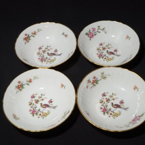 May include: Set of four white porcelain bowls with gold trim and floral designs. Each bowl features a colourful bird and floral pattern.