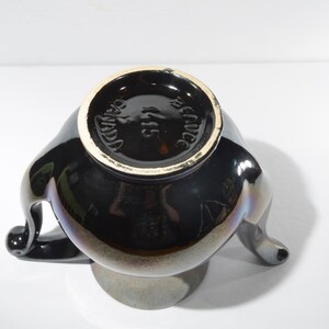 May include: Black ceramic vase with three handles and a gold rim. The bottom of the vase is marked "Made in Mexico".