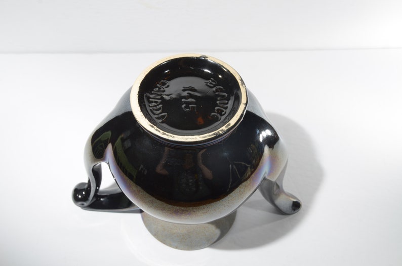 May include: Black ceramic vase with three handles and a gold rim. The bottom of the vase is marked "Made in Mexico".
