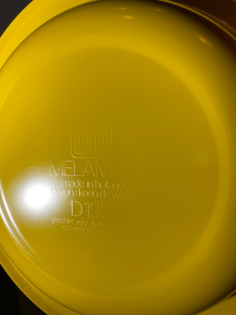 May include: Yellow melamine plate with the text "MELAMIN made in holland design: koen de wit D195 geschikt voor levensmiddelen convient pour aliments 1997/69/EG" printed on the bottom.