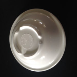 May include: White ceramic bowl with a raised lip and a circular base. The base has the text "CPL Made in USA" printed on it.