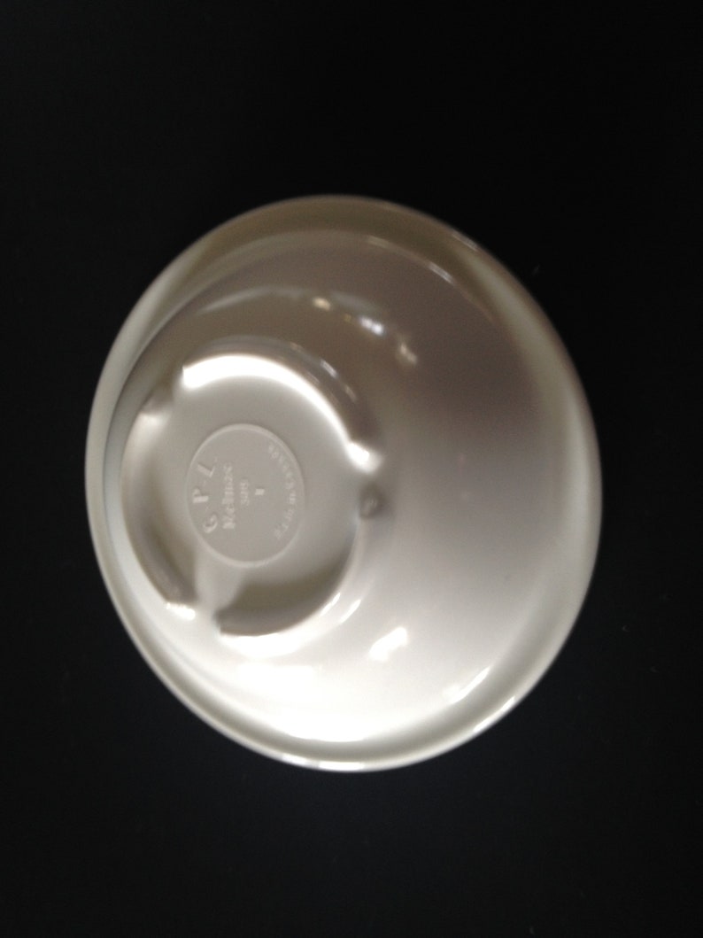May include: White ceramic bowl with a raised lip and a circular base. The base has the text "CPL Made in USA" printed on it.