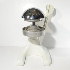 May include: A vintage white Juice King manual citrus juicer with a chrome top and a lever.