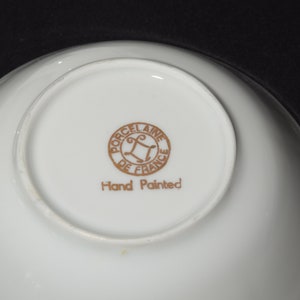 May include: A white porcelain bowl with a gold rim and a gold inscription that reads "Porcelaine de France" and "Hand Painted".