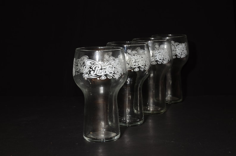 May include: Four clear glass Pepsi Cola glasses with the Pepsi Cola logo etched on the side.