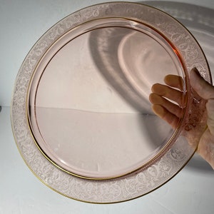 Puede incluir: Un plato de servir de vidrio rosa con un borde dorado y un delicado dise&ntilde;o grabado alrededor del borde.