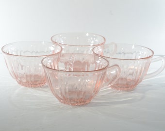 Puede incluir: Juego de cuatro tazas de té de vidrio rosa con un diseño acanalado. Las tazas tienen una forma redondeada y un asa.